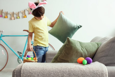 Cute little boy looking for hidden Easter eggs at homeの写真素材