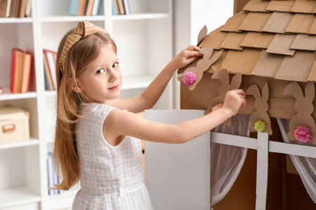 Cute little girl playing with cardboard house at homeの写真素材