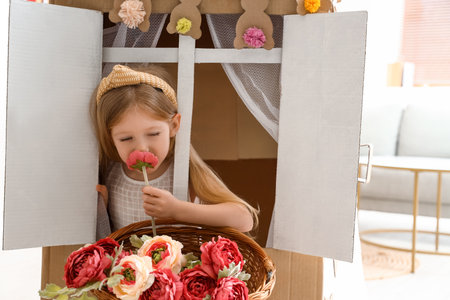 Cute little girl playing with cardboard house at homeの写真素材