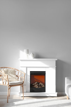 Wicker armchair and fireplace with vases near light wallの写真素材