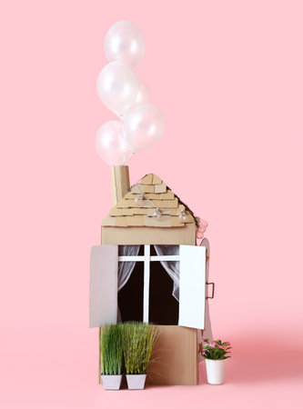 Cardboard toy house for child and plants on pink backgroundの写真素材