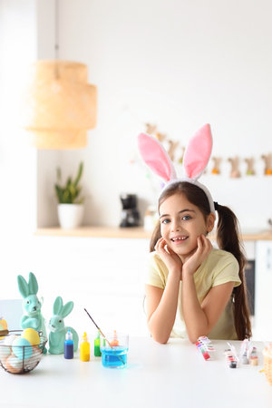 Funny little girl with bunny ears and Easter eggs at homeの写真素材