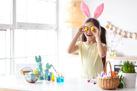 Funny little girl with bunny ears and Easter eggs at home