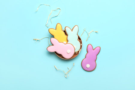 Box with delicious Easter cookies in shape of bunny on blue background