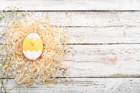 Nest with tasty Easter cookie on light wooden background