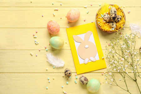 Beautiful Easter composition with greeting card, painted eggs and flowers on color wooden backgroundの写真素材
