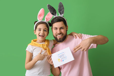 Little girl and her father pointing at greeting card with text HAPPY EASTER on green background