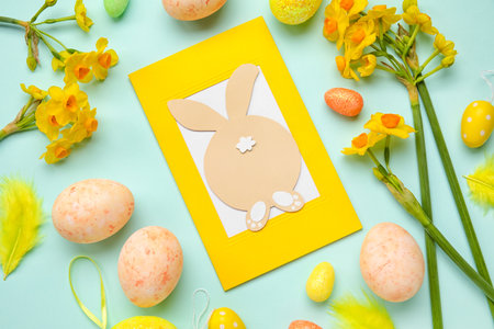 Beautiful Easter composition with greeting card, painted eggs and flowers on color background