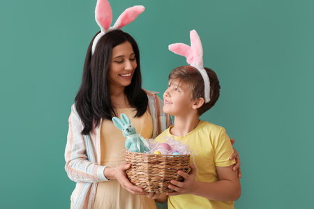 Little boy, his mother with basket and Easter eggs on green background