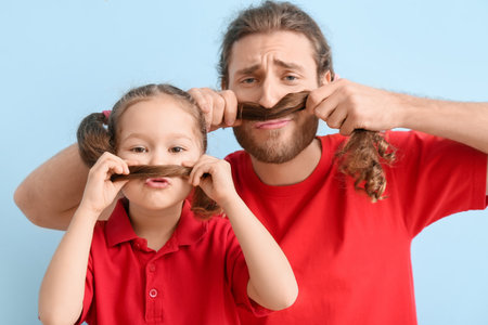 Funny man and her little daughter on blue background. April fools' day celebrationの写真素材
