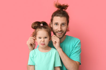 Funny man and her little daughter on pink background. April fools' day celebration