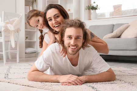 Happy young family lying on carpet at homeの写真素材