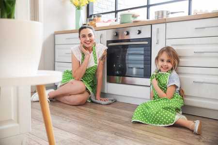 Little girl and her mother waiting for baking Easter cake in the kitchen