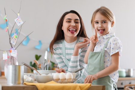 Little girl with her mother having fun while cooking in kitchen on Easter dayの写真素材