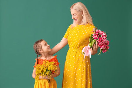 Little girl with her grandmother and flowers on green backgroundの写真素材
