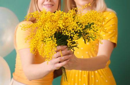 Young woman and her mother with flowers on green background, closeupの写真素材