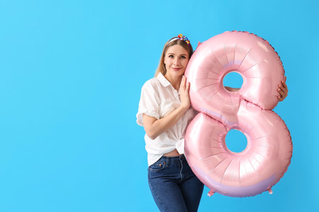 Beautiful woman with big balloon in shape of figure 8 on blue background. International Women's Dayの写真素材