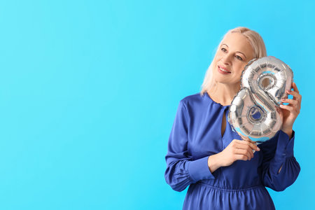 Mature woman with balloon in shape of figure 8 on blue background. International Women's Day