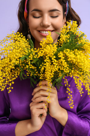 Beautiful young woman with bouquet of mimosa flowers on lilac backgroundの素材 [FY310192280096]