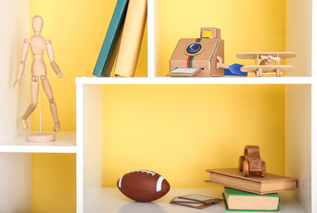 Shelf unit with different toys and books near color wallの写真素材
