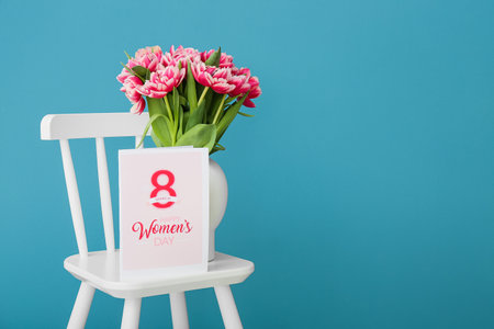 Greeting card with text HAPPY WOMEN'S DAY and vase with tulips on chair near color wallの写真素材