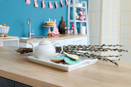 Tray with teapot, pussy willow branches and cookies on wooden counter in kitchenの写真素材