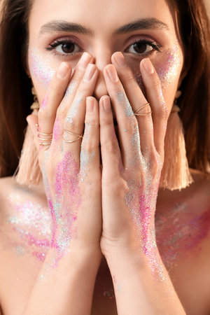Beautiful young woman with glitters on her face and bodyの写真素材