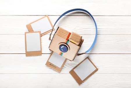 Cardboard photo camera with pictures on white wooden backgroundの写真素材
