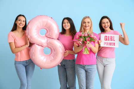 Beautiful women with bouquet of flowers, balloon and paper with text GIRL POWER on blue background. International Women's Day celebrationの写真素材