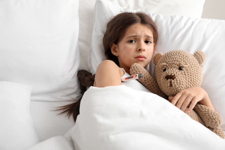 Little girl ill with chickenpox in bedの写真素材