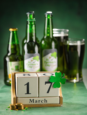 Calendar with date of St. Patrick's Day and coins on green background