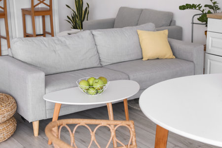 Comfortable sofa and table with basket of fresh apples in roomの写真素材