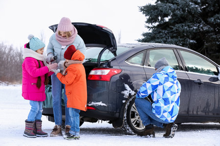 Mother pouring hot tea into her children's cups on snowy winter dayの写真素材