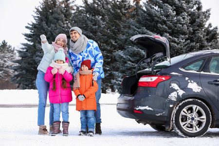 Parents with their little children and car on snowy winter dayの写真素材