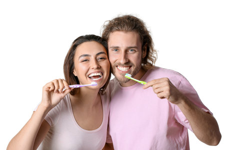 Happy young couple brushing teeth on white backgroundの写真素材
