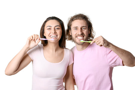 Happy young couple brushing teeth on white backgroundの写真素材