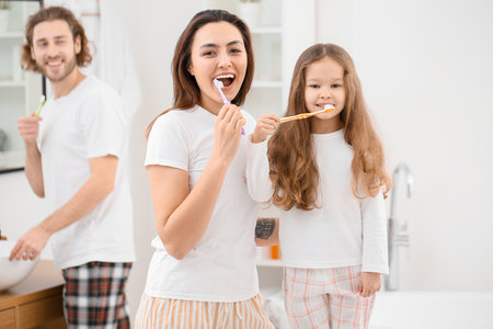 Little girl with her mother brushing teeth in bathroomの写真素材