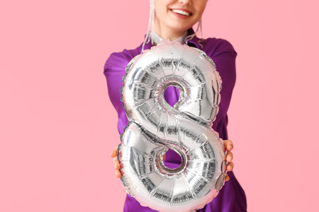 Stylish young woman with balloon in shape of figure 8 on pink background. International Women's Dayの写真素材