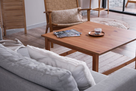 Modern table with candle, magazine and sofa in interior of roomの写真素材