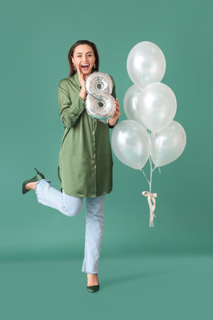 Happy young woman with balloons on green background. International Women's Day