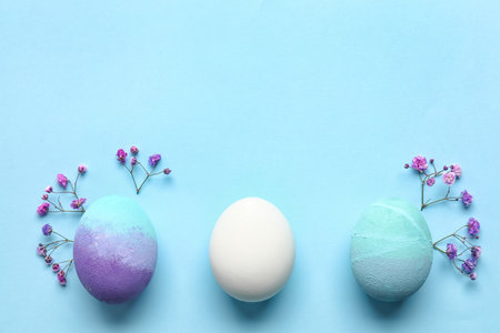 Beautiful Easter eggs and flowers on blue backgroundの写真素材