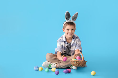 Funny little boy with bunny ears and Easter eggs on blue background