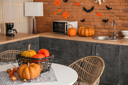 Basket with Halloween pumpkins on dining table in modern kitchenの写真素材