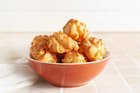 Bowl of tasty eclairs on table