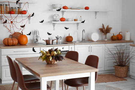 Interior of modern kitchen decorated for Halloween with pumpkins, dining table and countersの写真素材