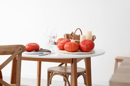 Basket with fallen leaves, pumpkins and burning candles on dining table in kitchenの写真素材