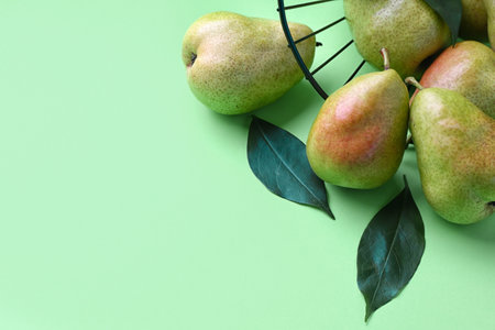 Overturned basket with tasty pears on color background