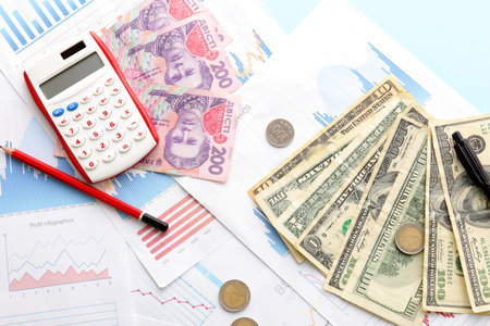 Different banknotes with coins, calculator and diagrams on blue background. Exchange rate conceptの写真素材