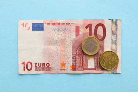 Euro banknote with coins on blue background. Exchange rate concept