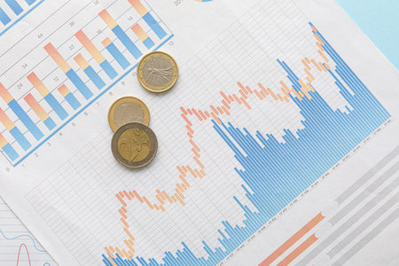 Coins and diagrams on blue background, closeup. Exchange rate conceptの写真素材